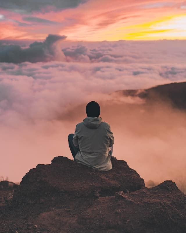 Man on mountain above the clouds watching sunrise.