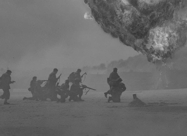 World War Two combat photo of soldiers under fire on a beach.